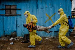 Medical staff carry James Dorbor, 8, suspected of having Ebola, into a treatment facility in Monrovia, Liberia, Sept. 5, 2014. Ebola ó the reality and the hysteria over it ó is having a serious economic impact on Guinea, Liberia and Sierra Leone, three nations already at the bottom of global economic and social indicators. (Daniel Berehulak/The New York Times)