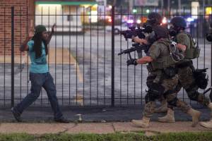 A man backs away as law enforcement officials close in on him and eventually detain him during protests over the death of Michael Brown, an unarmed black teenager killed by a police officer, in Ferguson, Mo., Aug. 11, 2014. The Federal Bureau of Investigation said on Monday that it had opened an inquiry into the weekend shooting of Brown. (Whitney Curtis/The New York Times)